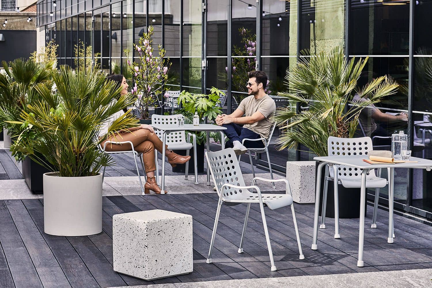 Smiling man and woman having a conversation at a café table outdoors.